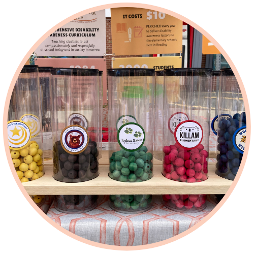 Street Faire Plastic jars of colored beads on a table outside at the 2022 Fall Street Faire